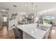 Bright open kitchen featuring a white quartz island, pendant lighting, and views of the dining and living areas at 16049 Volterra Pt, Bella Collina, FL 34756