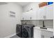 Well-equipped laundry room with modern appliances and ample cabinet space at 16049 Volterra Pt, Bella Collina, FL 34756