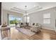Spacious living room featuring hardwood floors, tray ceiling, and sliding doors leading to the backyard at 16049 Volterra Pt, Bella Collina, FL 34756