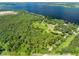 Aerial view of a property with lush trees, a well-manicured lawn, and a large body of water nearby at 2471 Jenscot Rd, St Cloud, FL 34771