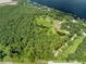 Aerial view of a property with lush trees, a well-manicured lawn, and a large body of water nearby at 2471 Jenscot Rd, St Cloud, FL 34771