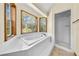 Bright bathroom showcasing a corner bathtub, and shower, complemented by natural light from two windows at 2471 Jenscot Rd, St Cloud, FL 34771