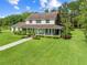 Charming two-story home featuring a welcoming front porch, lush lawn, and mature trees at 2471 Jenscot Rd, St Cloud, FL 34771