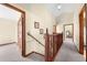 Upstairs hallway with wood railing and neutral carpet that leads to bedrooms, all with wood-trimmed doorways at 2471 Jenscot Rd, St Cloud, FL 34771