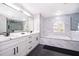 Elegant bathroom with dual sinks, marble tiling, large mirror, soaking tub and walk-in glass shower at 2503 Calla Lily Cv, Kissimmee, FL 34758