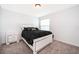 Cozy bedroom with a black patterned bed, window with blinds, and light gray carpet flooring at 2503 Calla Lily Cv, Kissimmee, FL 34758