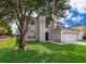 Two story stucco home with green lawn, and mature shade tree at 2503 Calla Lily Cv, Kissimmee, FL 34758