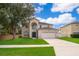 Well-maintained two-story home with landscaped lawn, arched entry, and attached garage at 2503 Calla Lily Cv, Kissimmee, FL 34758