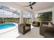 Relaxing screened lanai with comfortable seating area overlooking the beautiful backyard, pool, and water view at 2503 Calla Lily Cv, Kissimmee, FL 34758