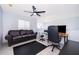 Living room with dark leather sofa, desk space, ceiling fan, and tile flooring at 2503 Calla Lily Cv, Kissimmee, FL 34758