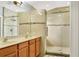 Tiled bathroom featuring double sinks, granite counters, a large mirror, and a glass shower with a rainfall showerhead at 2722 Corybrooke Ln, Kissimmee, FL 34744