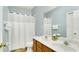 Clean bathroom with double sinks, a large mirror, and a shower with a white curtain at 2722 Corybrooke Ln, Kissimmee, FL 34744