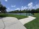 A fenced in, well-maintained tennis court on a sunny day with blue skies and manicured green grass at 2722 Corybrooke Ln, Kissimmee, FL 34744