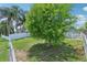 Spacious backyard with lush green lawn, mature shade tree, and white picket fence, offering privacy and charm at 3038 Elbib, St Cloud, FL 34769