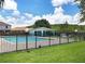 Community pool surrounded by black metal fence with a small cabana and clear blue sky at 3038 Elbib, St Cloud, FL 34769