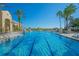 Sparkling community pool with multiple lounge areas and lush palm trees against a clear blue sky at 3617 Northwoods Dr, Kissimmee, FL 34746