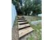 Wooden steps lead up a small hill in the backyard towards a white privacy fence at 453 Alston Dr, Orlando, FL 32835