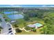 Aerial view of a community pool, tennis court, and lake surrounded by lush greenery and well-maintained homes at 5103 Jones Rd, St Cloud, FL 34771