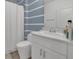Clean bathroom featuring a white vanity, modern fixtures, and stylish blue and white striped accent wall at 5225 Tuscany Ln, Davenport, FL 33897