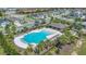 Aerial view of a stunning community pool with poolside seating, palm trees and lush green surroundings at 5225 Tuscany Ln, Davenport, FL 33897