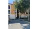 Three-story condo building with covered stairwell, tan and white exterior, and mature tree near parking area at 6169 Metrowest Blvd # 208, Orlando, FL 32835