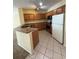 Kitchen featuring wood cabinets, stainless steel appliances, granite counters, and tile floors at 6169 Metrowest Blvd # 208, Orlando, FL 32835
