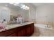 This bathroom features dual sinks, a soaking tub, granite countertops, and tiled floors at 6834 Habitat Dr, Harmony, FL 34773