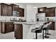 Modern kitchen with stainless steel appliances, granite countertops, island with seating, and dark wood cabinetry at 7622 Oakmoss Loop, Davenport, FL 33837