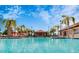 Large community pool with volleyball net, lounge chairs, and palm trees at 7622 Oakmoss Loop, Davenport, FL 33837