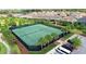 Aerial view of well-maintained tennis courts in a fenced-in area with surrounding landscaping and parking at 7622 Oakmoss Loop, Davenport, FL 33837
