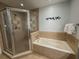 Relaxing bathroom features a tub and a walk-in shower with decorative tile and updated fixtures at 7650 Whisper Way # 102, Reunion, FL 34747