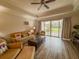 Cozy living room with wood floors, a ceiling fan, and sliding glass doors leading to an outdoor patio at 7650 Whisper Way # 102, Reunion, FL 34747