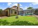 Backyard view showcasing a screened-in pool, lush lawn, fire pit, and well-maintained landscaping at 7846 Snowberry Cir, Orlando, FL 32819