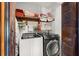 Efficient laundry room featuring a washer, dryer, and storage shelves with folded towels at 7846 Snowberry Cir, Orlando, FL 32819