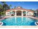 Community pool with lounge chairs and umbrellas under a blue sky, surrounded by a clubhouse at 8491 Oasis Key Cv, Kissimmee, FL 34747