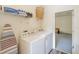 Bright laundry room with white washer/dryer, storage shelves, ironing board, and a view into the bonus room at 8491 Oasis Key Cv, Kissimmee, FL 34747
