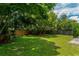 A lush green backyard with mature trees, a well-maintained lawn, and a wooden fence at 1016 Ohanlon Ct, Oviedo, FL 32765