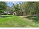 Beautiful large backyard with lush green grass, mature trees, and a bricked area surrounded by a wood fence at 166 Paradise Island Dr, Haines City, FL 33844