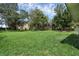 Large backyard featuring lush green grass, mature trees, and a sturdy privacy fence around the perimeter at 166 Paradise Island Dr, Haines City, FL 33844