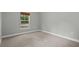 This is an empty bedroom featuring neutral carpet, a window, baseboards, and grey walls at 1800 Banyan St, Orange City, FL 32763