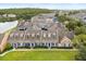 Aerial view of a neighborhood of townhomes with blue shutters, green lawns, and a pond at 2050 Island Walk Dr, Orlando, FL 32824