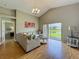 Bright living room featuring wood floors, vaulted ceiling, comfortable sofa, and sliding glass doors at 2054 Hammock Moss Dr, Orlando, FL 32820