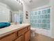 Bright bathroom with wood vanity, framed mirror, and a shower-tub with seashell shower curtain at 2649 Hemingway Ave, Haines City, FL 33844