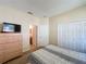 Well-lit bedroom featuring closet space, a dresser with a TV, and an open view of the ensuite bathroom at 2649 Hemingway Ave, Haines City, FL 33844