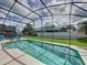 Inviting pool with screened enclosure surrounded by lush landscaping and privacy fence at 2649 Hemingway Ave, Haines City, FL 33844