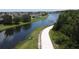 Scenic view of a paved walking path beside a waterway, surrounded by lush greenery and trees at 2924 White Cedar Cir, Kissimmee, FL 34741