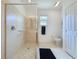 Tiled shower with grab bar inside a bathroom with a window, toilet, and dark floor mat at 2924 White Cedar Cir, Kissimmee, FL 34741