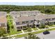 An aerial view of townhomes with manicured lawns and mature trees near a lake at 2966 Aqua Virgo Loop # 16, Orlando, FL 32837