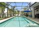 Screened-in pool with lounge chairs, palm trees, and a blue umbrella offers an outdoor oasis at 3310 Cat Brier Trl, Harmony, FL 34773