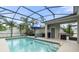 Relaxing screened-in pool area with a pool, palm trees, patio chairs and an umbrella at 3310 Cat Brier Trl, Harmony, FL 34773